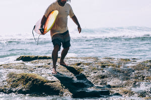 files/man-carrying-surfboard-emerges-from-ocean-waves.jpg